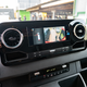 another view of the dashboard of the 2023 mercedes benz sprinter awd van. the screen in the center of the dash shows a view from the camera on the rear of the vehicle, letting the driver see the person loading cargo in the back of the van.